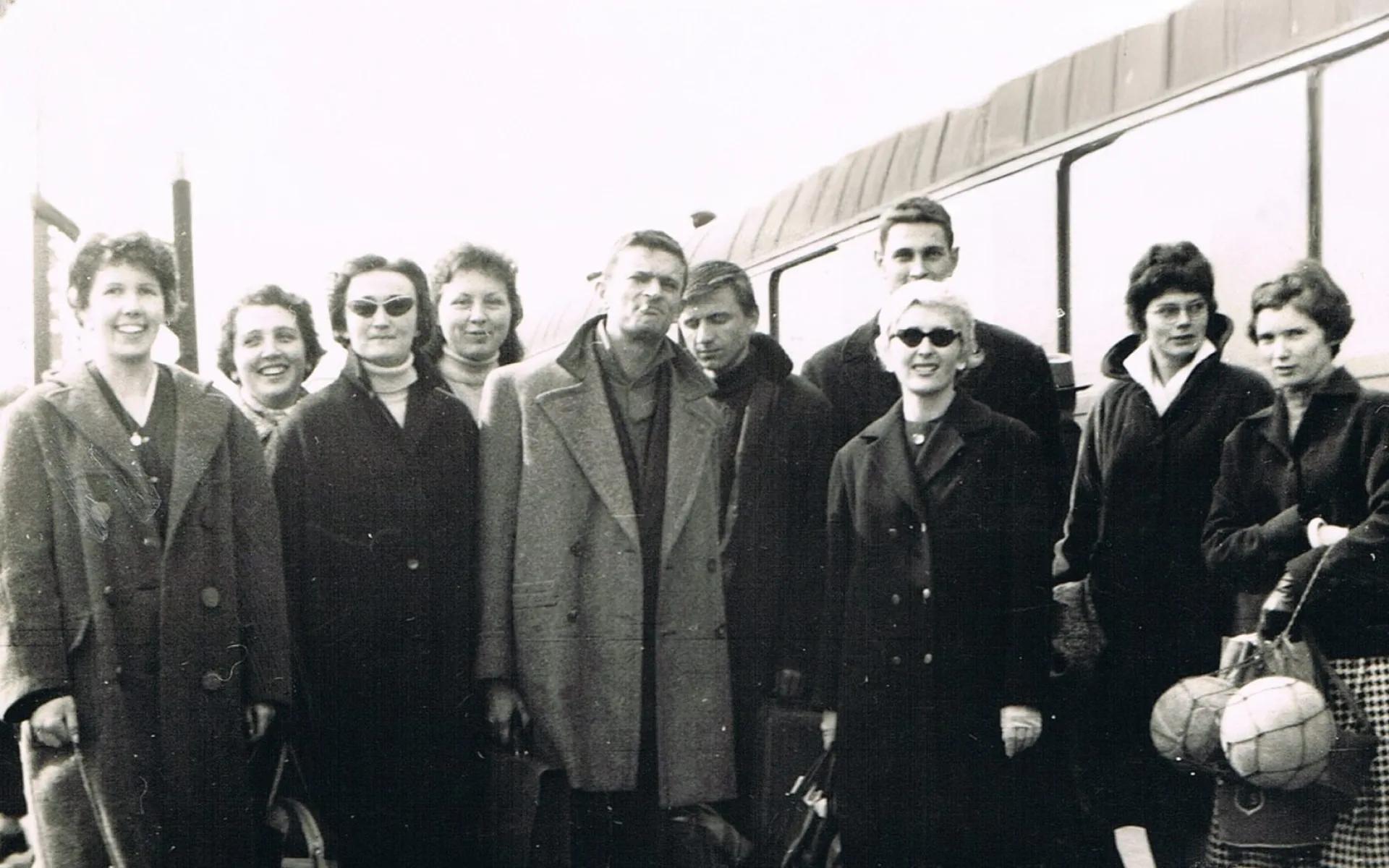 Une photo en noir et banc de l'équipe féminine du REC en 1959. Tout le monde porte de gros manteaux. Les entraineurs sont au mlieu de la photo avec les joueuses sur les côtés. Une joueuse porte un filet de ballons.